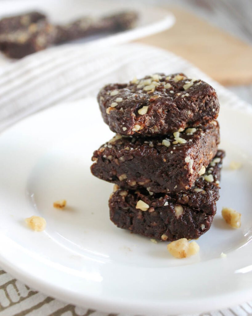 three brownies stacked on a white plate with walnuts 