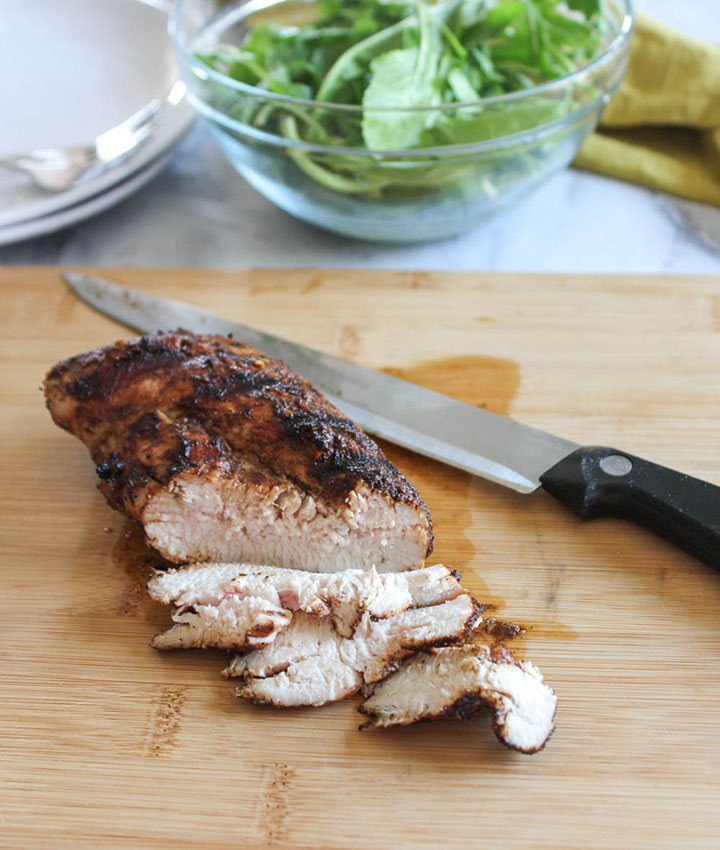 grilled chicken breast on a cutting board sliced with a knife