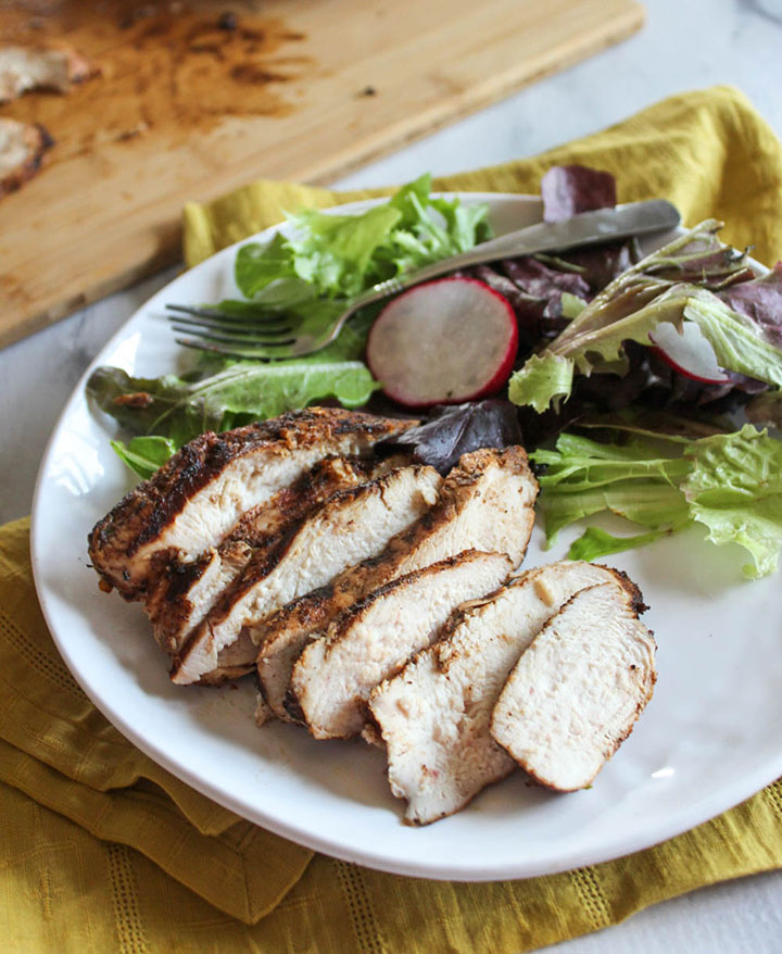 sliced jerk chickenon a plate with a salad