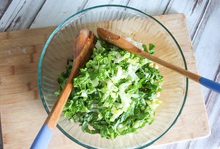 Lettuce in a bowl on top of the remaining salad ingredients