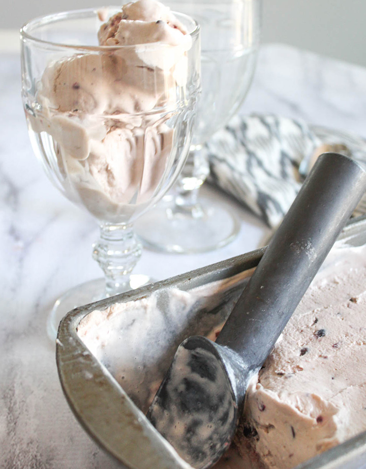 Ice cream in a cup woth a container of ice cream in front with a scoop