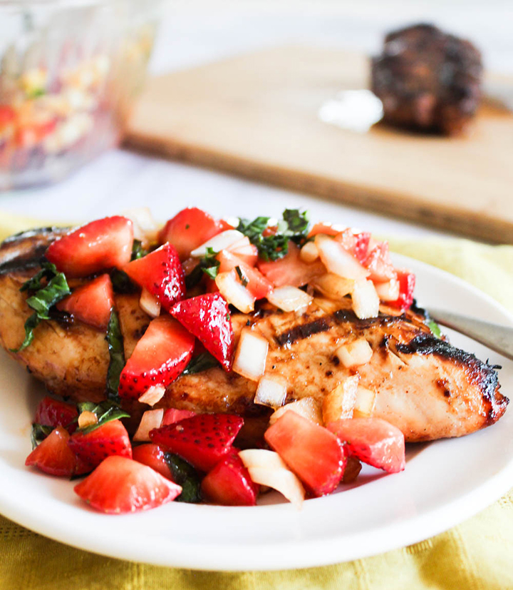 Grilled chicken breast topped with strawberry salsa on a white plate