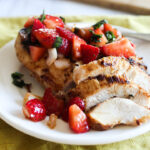 sliced chicken on a plate with strawberry salsa