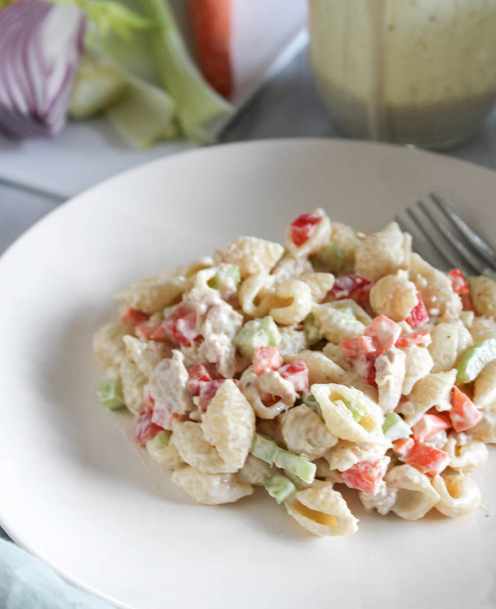 a close up view of the pasta salad on a white plate with a fork