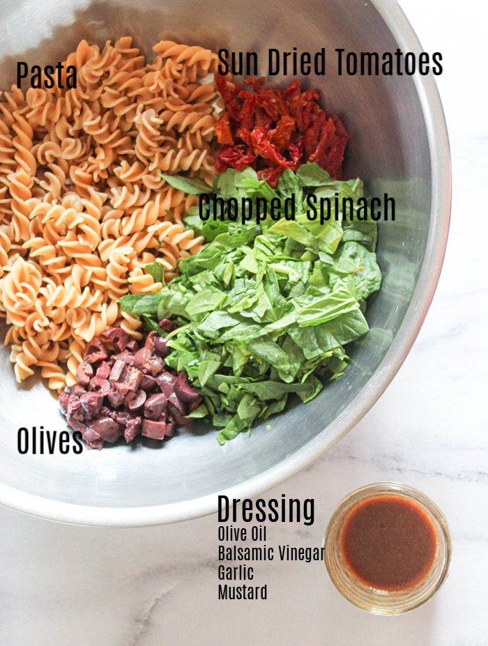 spinach pasta salad ingredients in a mixing bowl