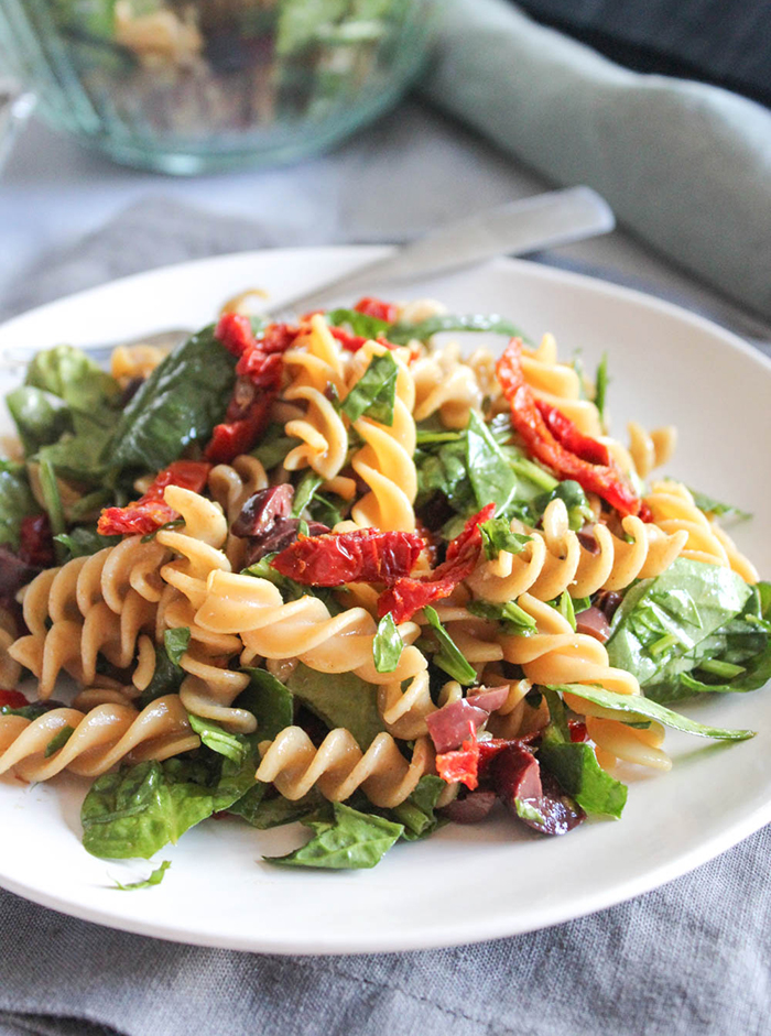 spinach pasta salad on a white plate