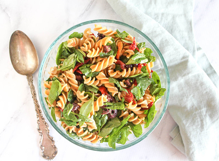 spinach Pasta salad in a bowl with a spoon on the side