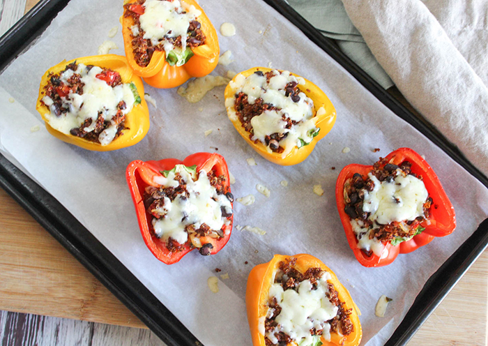 An overhead view of stuffed peppers on a baking pan with melted cheese