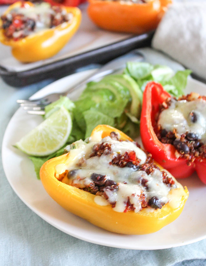 vegetarian stuffed eppers on a plate with a salad and lime wedge