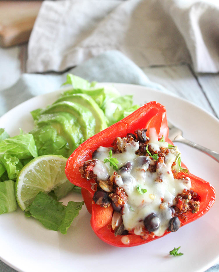 A close up of a stuffed pepper with melted cheese on a white plate