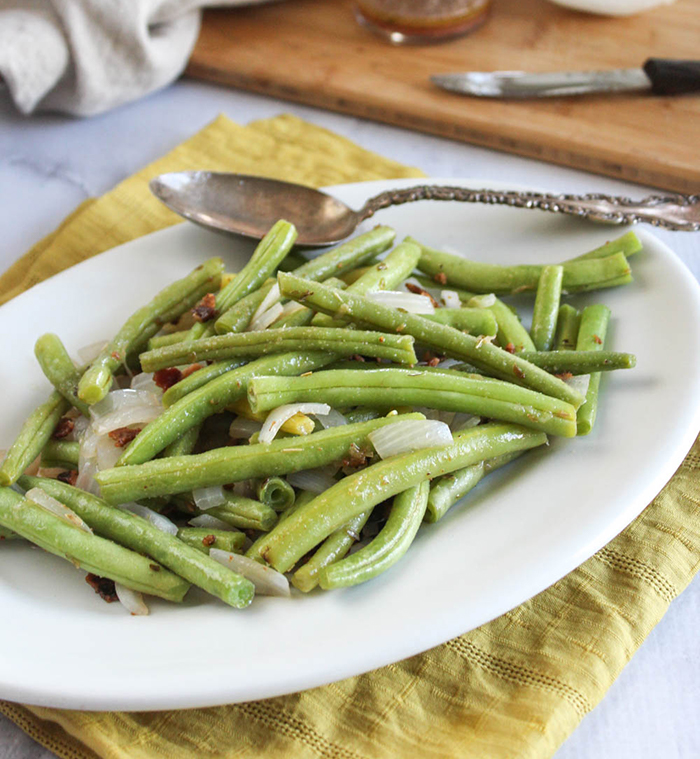 Green Beans on a white platter with a spooon 