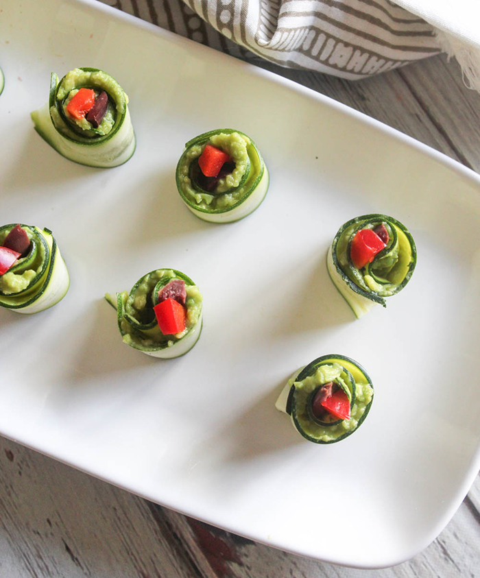 an overhead view of zucchini roll ups on a white platter