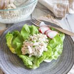 chicken salad on a plate with radishes and a fork on the side