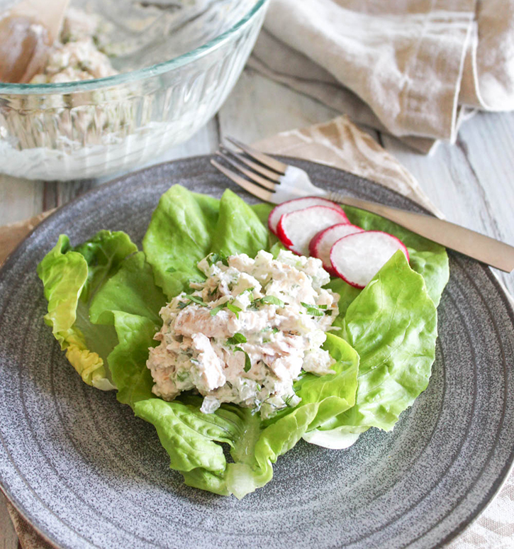 chicken salad on a plate with radishes and a fork on the side