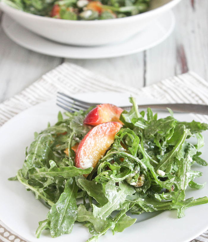 a close up of peach arugula salad on a plate