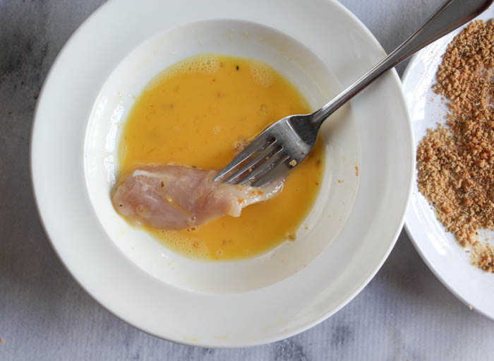 a picture of chicken tenders dipping into egg
