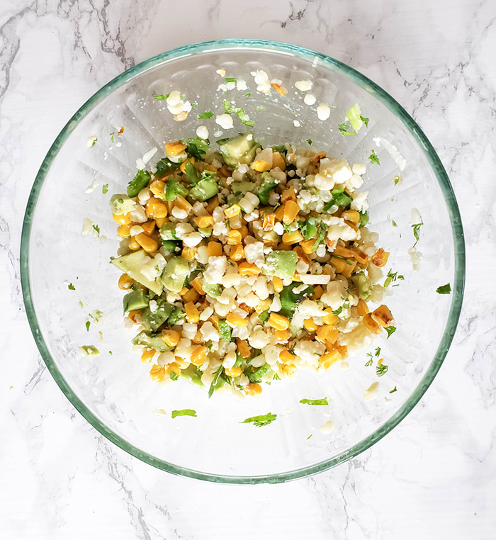 an overhead view of the corn salad mixed in a glass bowl