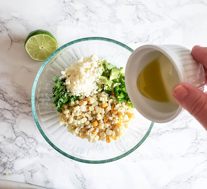 corn slaad ingredients in a bowl with lime juice being poured in