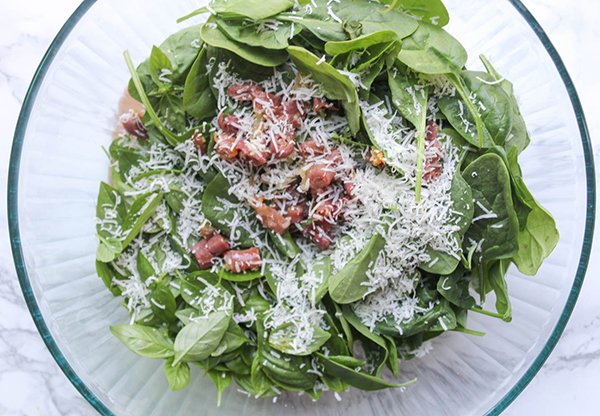 spinach salad in a bowl with cheese on top