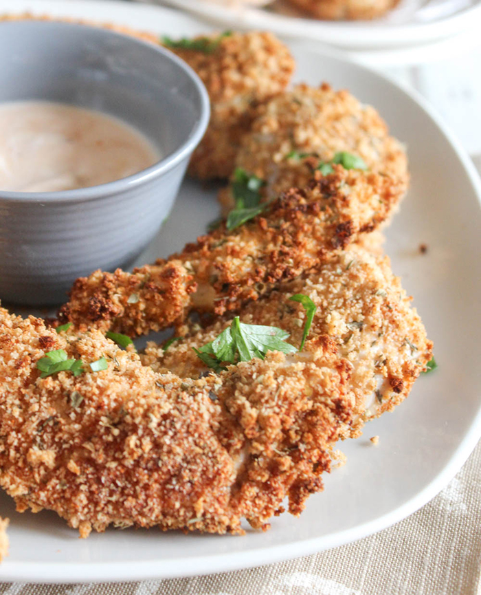 a close up picture of chicken tenders on a plate with dipping sauce