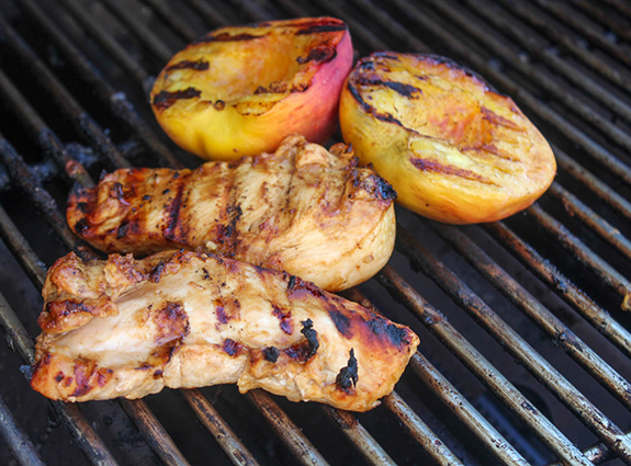 a picture of chicken and peaches on a grill