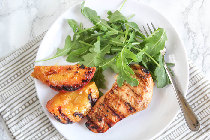 an overhead viewof grilled peaches and chicken on a white plate