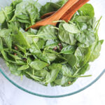 overhead view of mixed spinach salad in a galss bowl