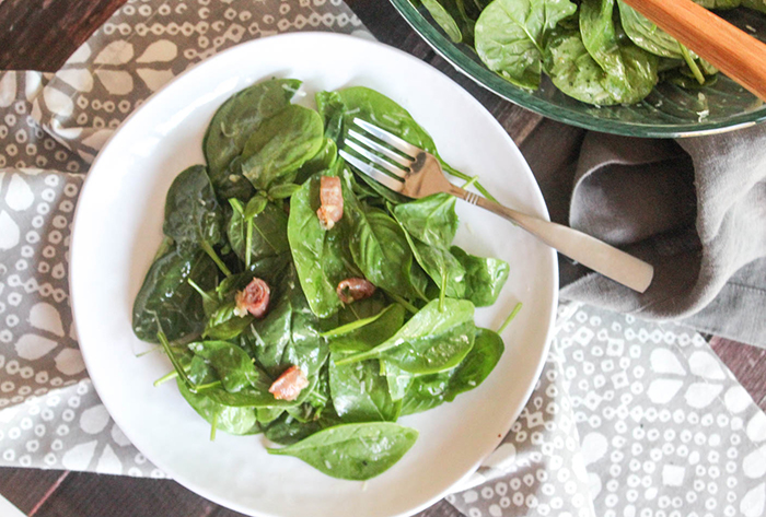 an overhead view of the spinach salad on a white place 