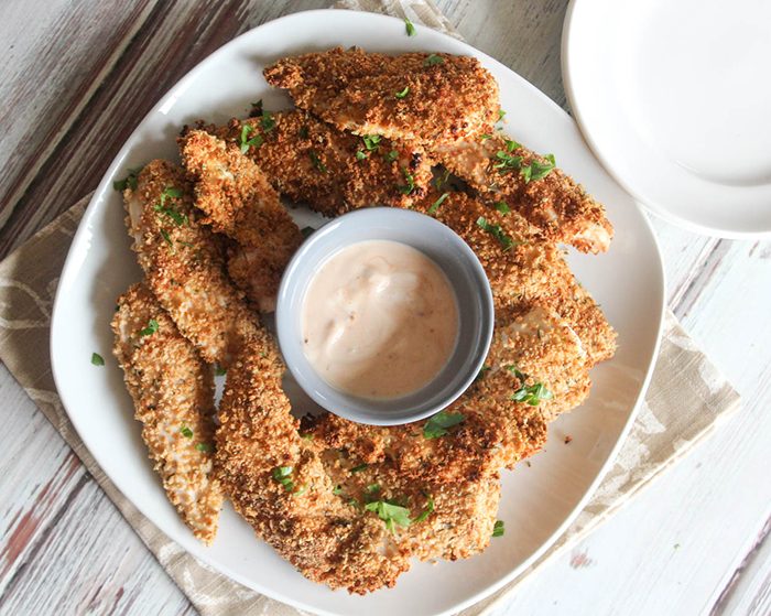 spicy chicken tenders on a white plate with dipping sauce