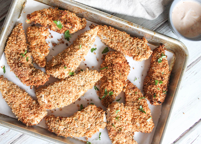Baked chicken tenders on a baking sheeet.
