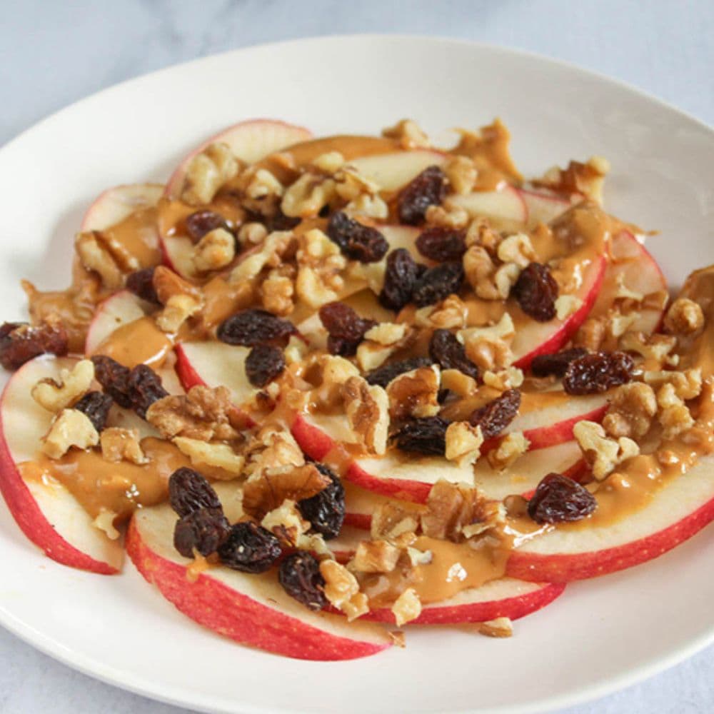 the finished product, apple slices with peanut butter, walnuts and raisins on top