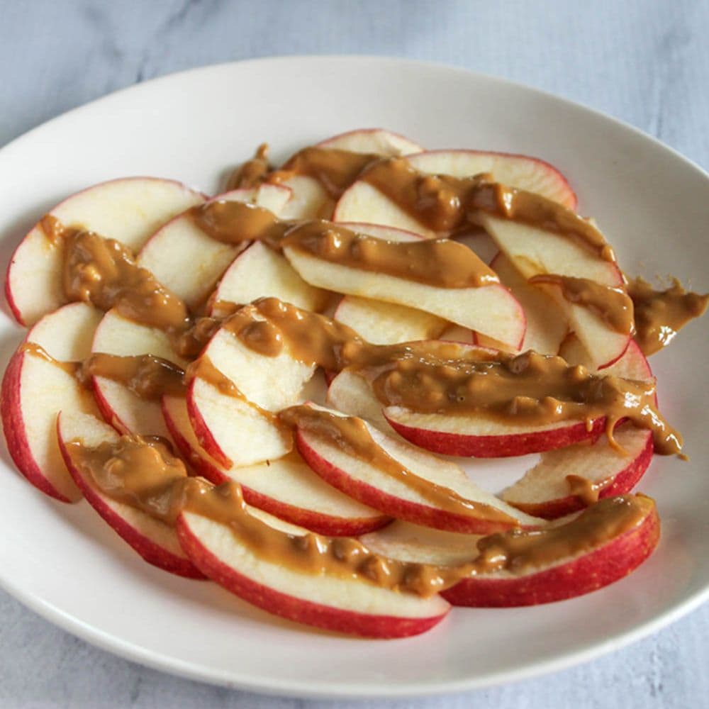 a picture of apple slices on a plate with a drizzle of peanut butter on them
