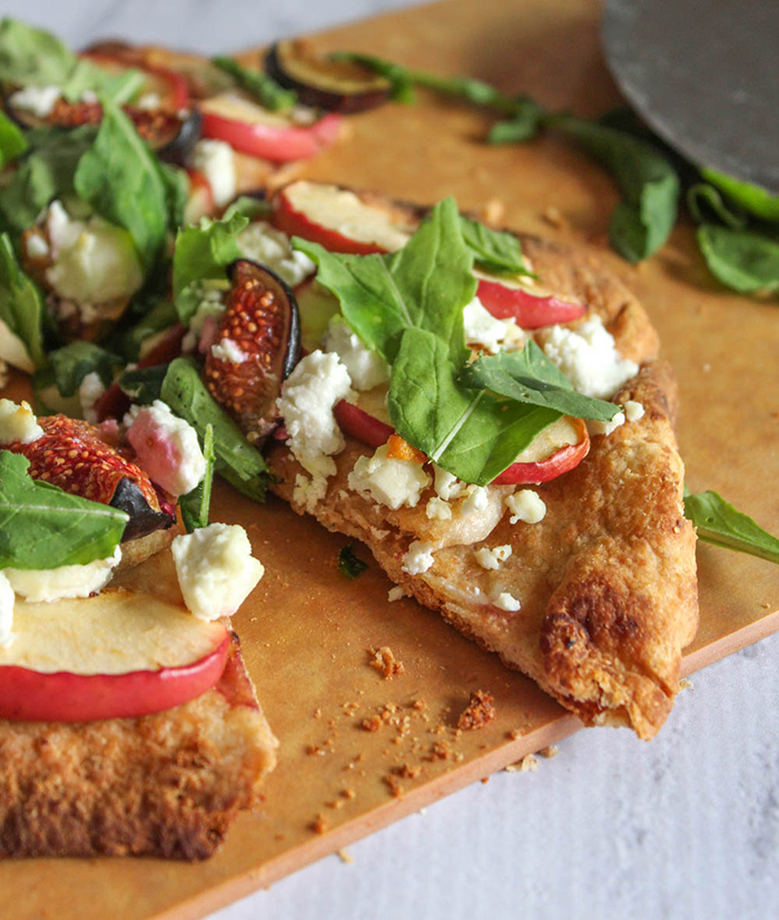 a slice of apple fig flatbread on a cutting board