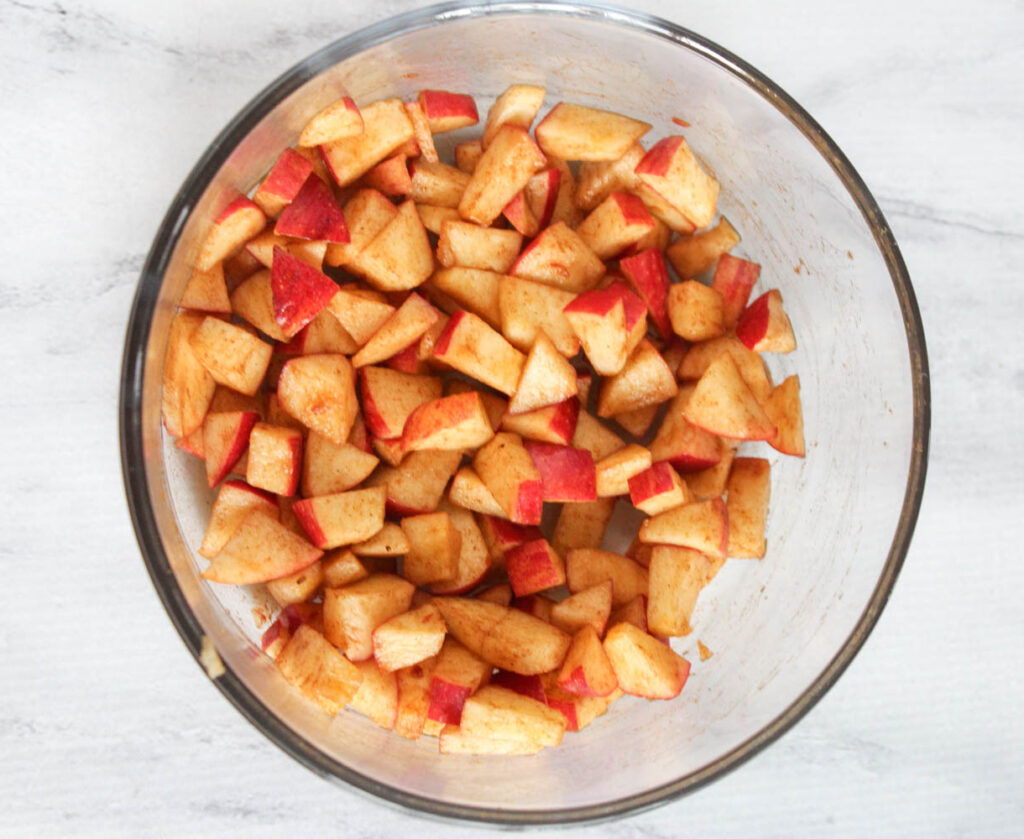 a bowl of apples coated in cinnamon and maple syrup