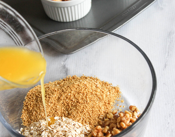 butter pouring into a bowl of oats and crumbs