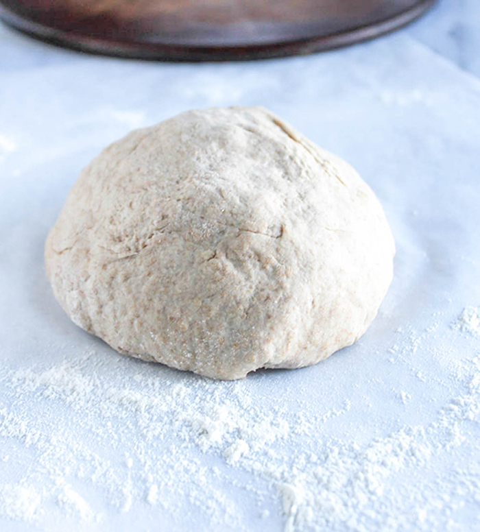 a dough ball on a piece of white parchment with flour