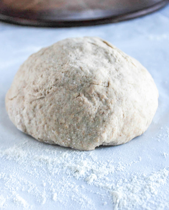 a close up of the dough ball on white parchment with flour