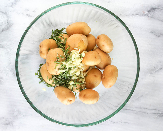 baby potatoes in a bowl with garlic and rosemary on top