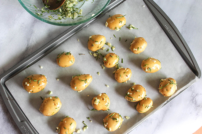 Baby potatoes on a roasting pan with garlic and herbs