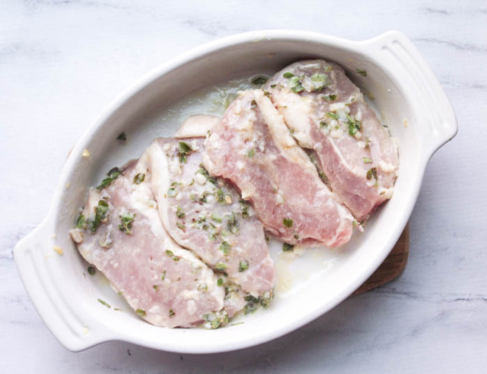 pork chops in a bowl marinating