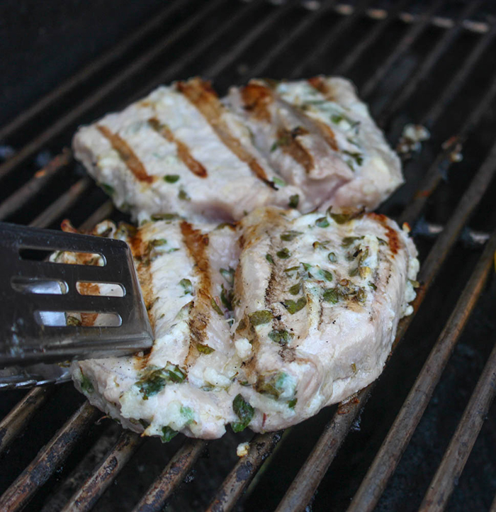 This image is final stage of grilling pork chops on grill rack to reach 145 degrees Fahrenheit.