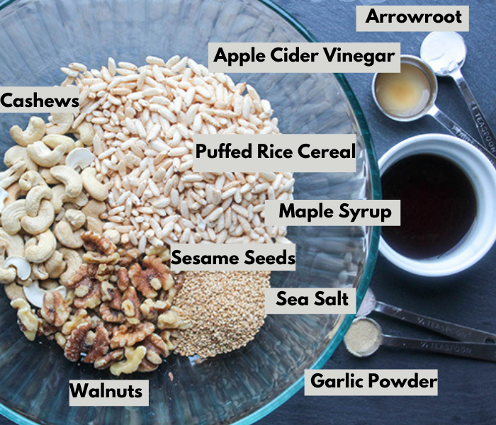 the ingredients in a bowl from left to right: cashews, arrowroot, apple cider vinegar, puffed rice cereal, maple syrup, sesame seeds, sea salt, garlic powder and walnuts