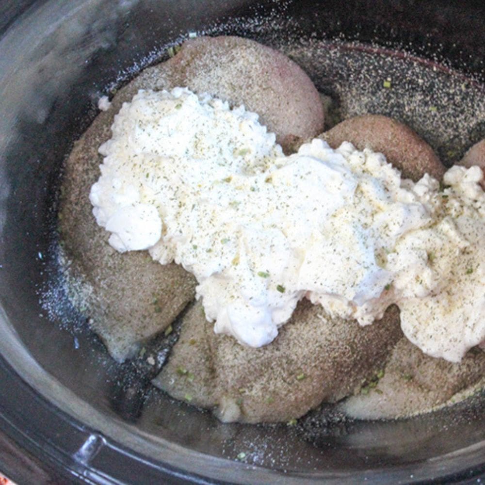 crack chicken step 2 partially cooked chicken in a slow cooker with cheese on top