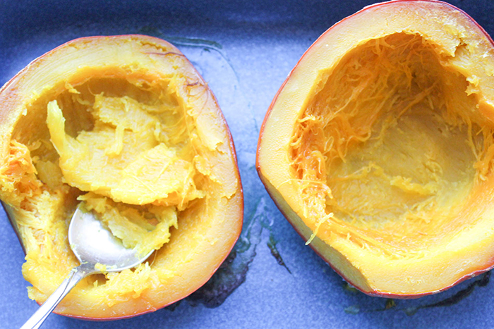 two pumpkin halves with spoon scooping out pulp