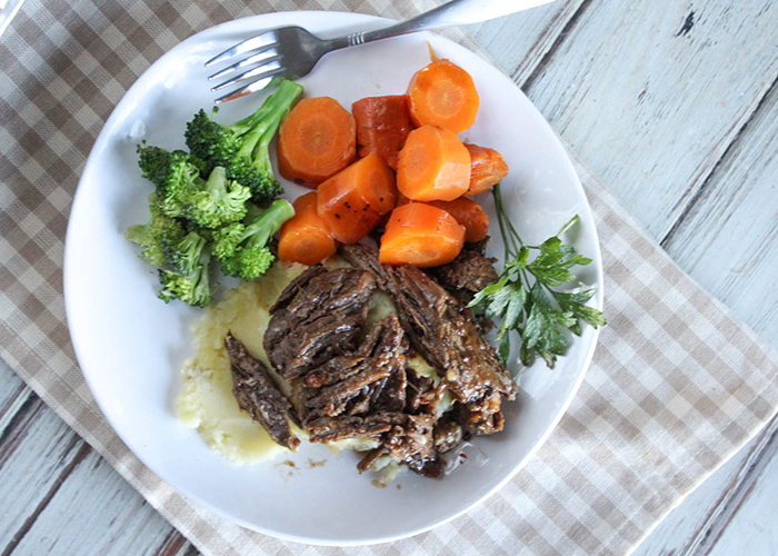 an overhead view of braised chuck roast on a plate with carrots