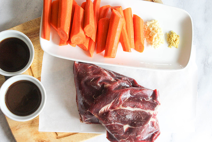 AN overhead view of the uncooked ingredients: beef chuck roast, Kevin's teriyaki sauce, carrots, garlic and ginger