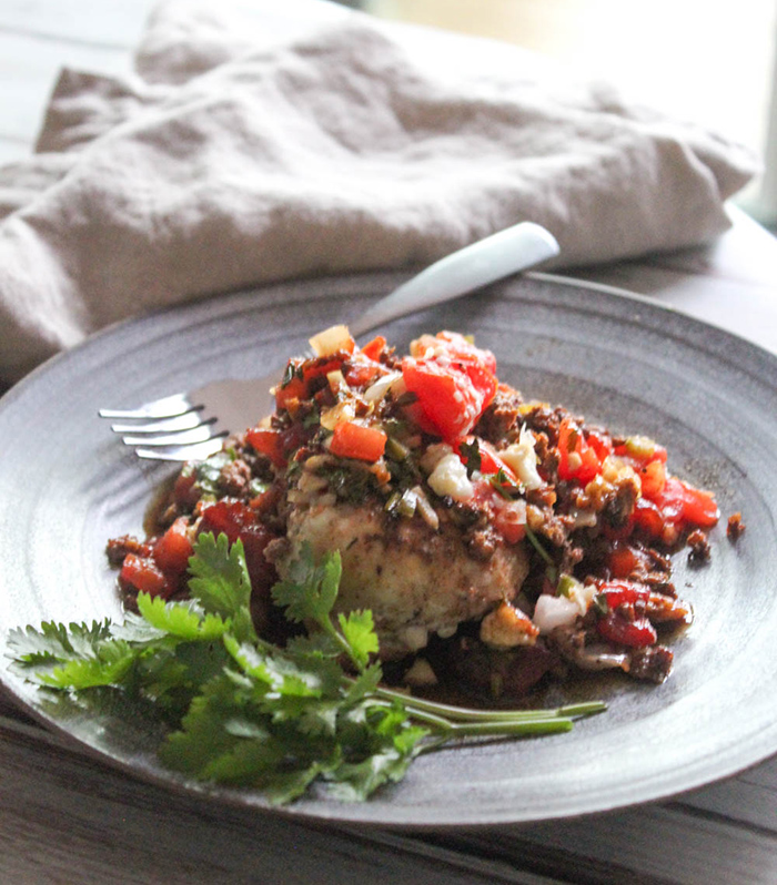 chicken breast on a plate covered with tomatoes, and chorizo sausage