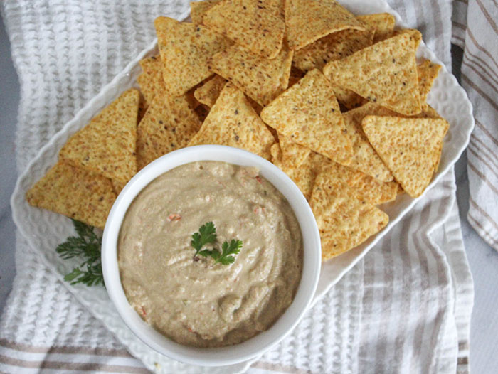 An overhead view of queso dip in a bowl on a try with chips