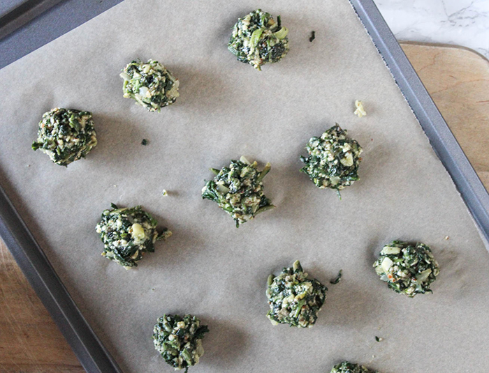 uncooked spinach balls on a baking sheet