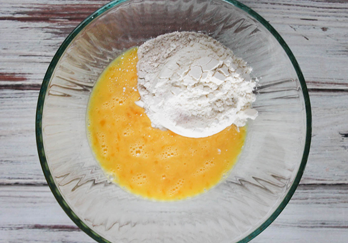 an overhead view of beaten eggs and flour in a bowl